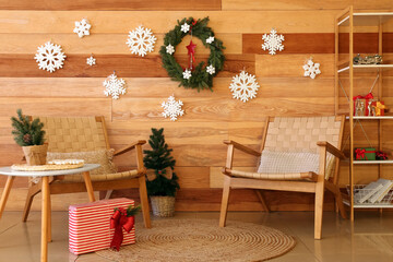 Interior of living room with armchairs, small fir tree and Christmas decor