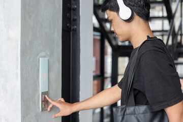 Obraz premium Asian young man pressing the elevator button