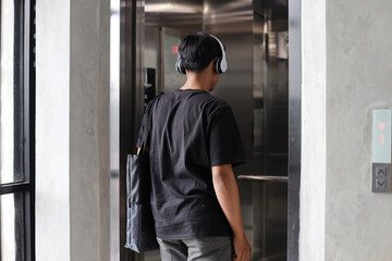 Back view of Millennial young people wearing modern suits entering the elevator © Gatot