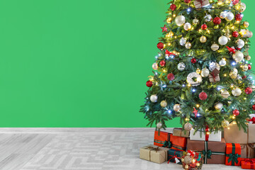 Beautiful Christmas tree and gift boxes near green wall