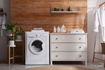 Laundry room interior with washing machine and stylish furniture