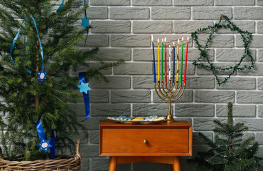 Menorah and cookies for Hanukkah celebration with Christmas trees in room