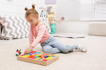 Cute little girl playing with colorful building blocks at home