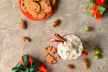 Cup of tasty cacao with candy cane and Christmas decor on grey background