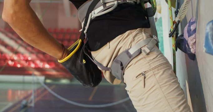 A young man climbs up the artificial surface of the climbing wall