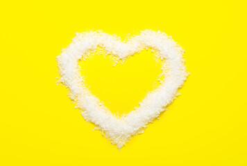Heart made of snow on yellow background