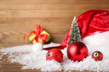 Red Christmas decorations and snow on wooden background