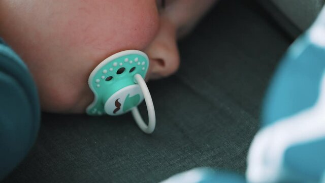 Cute kid sleeping with a pacifier while traveling. Adorable baby sleeping peacefully. Slow-motion closeup footage. Childhood, carefree days concept. 