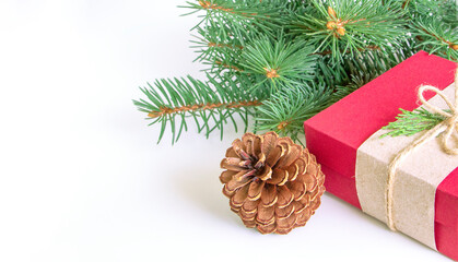 Fototapeta na wymiar Close up red gift box and pine cone with green Christmas tree branches on white background. Copy space