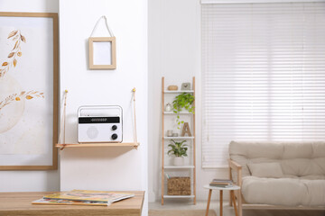 Stylish white radio on wooden shelf in living room interior