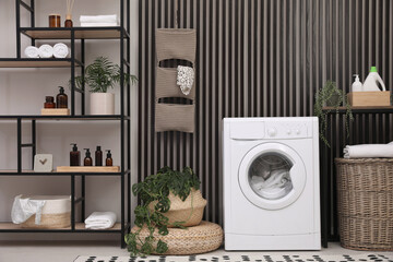 Laundry room interior with washing machine and stylish furniture