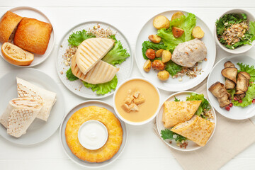 Set lunch - soup, chicken, potatoes, lettuce, cheese, roll, cakes, vegetables and casserole. Top view