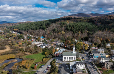 Fototapeta na wymiar Aerial view of charming small town Stowe in Vermont. Mountains with fall multicolor trees and blue sky background