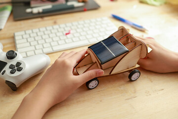 Kid assembly a solar toy car through online e-learning at home. Student doing school project or learning science with online tutorial. Education and technology concept. Soft focus image.
