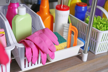 Different cleaning supplies on wooden table in kitchen, closeup