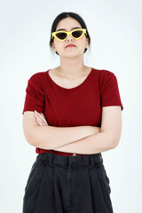Portrait studio shot of Asian young cool fashionable stylish ponytail hairstyle female model in casual outfit wear yellow fashion sunglasses standing crossed arms look at camera on white background