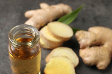 Glass bottle of ginger essential oil on grey table, closeup. Space for text