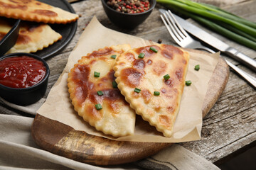 Delicious fried chebureki with ketchup served on wooden table