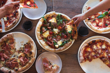 Selection of different pizzas on a wood background and ingredients.
