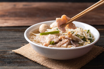 Rice noodles soup with pork and pork ball in a bowl on wooden background, Thai noodles soup