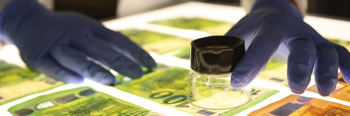 Hand with magnifying glass checks authenticity of money