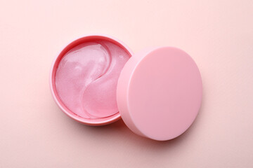Obraz na płótnie Canvas Under eye patches in jar with lid on light pink background, top view. Cosmetic product