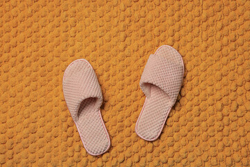 Fototapeta na wymiar Slippers on soft orange bath mat, flat lay