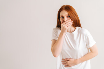 Portrait of unwell young woman feeling painful cramp in stomach, grimacing and writhing in pain feeling stomach ache indigestion periods miscarriage, on white isolated background in studio.