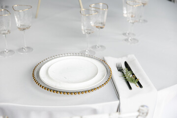 Beautiful festive table setting. A luxurious dining set with cutlery, napkin, dishes and covered...