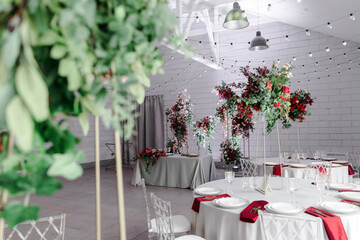 Canned round tables in the white hall. Wedding decorations made of flowers on the tables. the concept of the holiday.