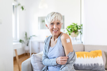 Senior woman looking happy after getting vaccine. Mature woman with band-aid on her arm after...