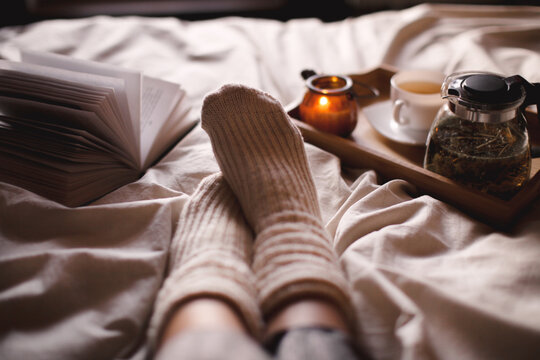 Soft photo of woman on the bed with book and cup of tea