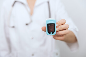 Pulse oximeter with hand of doctor isolated on white. The concept of portable digital device to measure person's oxygen saturation. Measuring oxygen saturation, pulse rate and oxygen levels.
