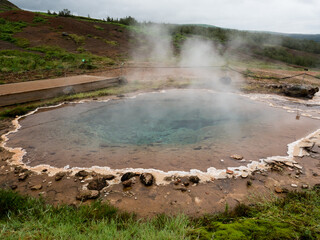 Fototapeta na wymiar Steaming colorful hot spring pool in Geysir geothermal area, Iceland