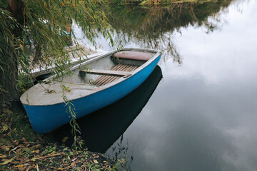 Light blue wooden boat on lake near pier, space for text