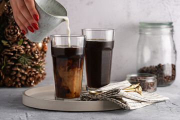 Pouring milk into a tall glass with cold coffee making frappe - iced cappuccino