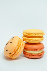 several multi-colored macarons on a white background. red, yellow and orange desserts with different flavors. beautiful and bright dessert after breakfast. delicious for tea or coffee.