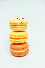 several multi-colored macarons on a white background. red, yellow and orange desserts with different flavors. beautiful and bright dessert after breakfast. delicious for tea or coffee.