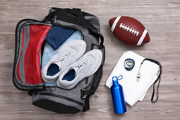 Grey gym bag and sports equipment on wooden background, flat lay