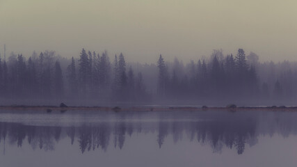 Fog and gray weather where the bay's opposite shoreline is reflected in Ytterbodafjärden's water level.