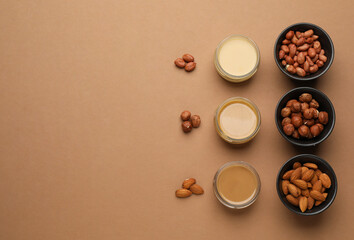 Obraz na płótnie Canvas Different types of delicious nut butters and ingredients on brown background, flat lay. Space for text