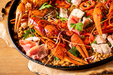 Catalan paella with shrimp and blue fideua on a rustic wooden background.