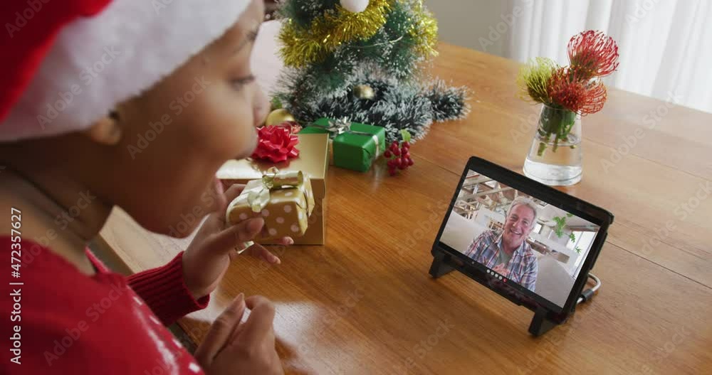 Poster African american woman with santa hat using tablet for christmas video call with man on screen