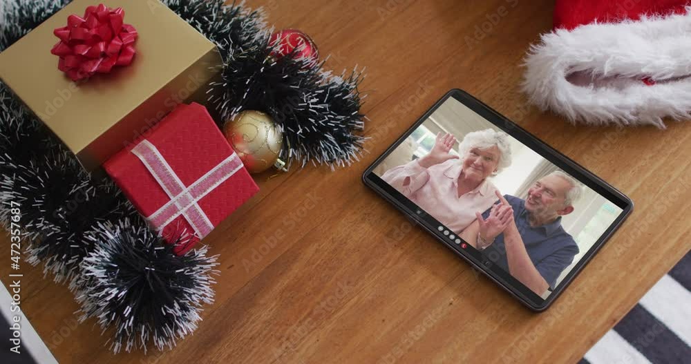 Wall mural Smiling senior caucasian couple waving on christmas video call on tablet