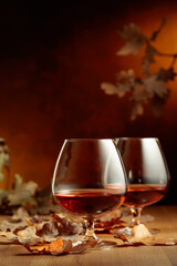 Glasses of brandy on an old oak table with fallen oak leaves.