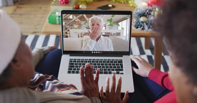African american mother and daughter using laptop for christmas video call with woman on screen