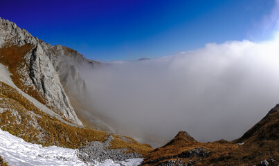 very dense fog under blue sky while hiking on a mountain in autumn panorama