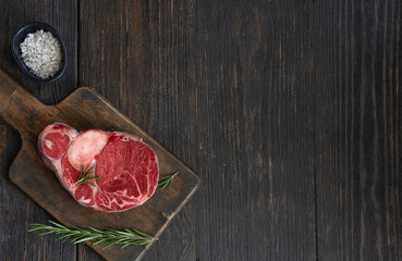 Fresh osso buco  steak meat on wooden cut board with rosemary and salt