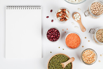 Vegan protein source. Beans, peas, chickpeas, lentils, mung bean, peanut in bowl on white background with notepad. Healthy vegetarian food. copy space