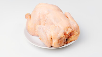 carcass of raw chicken on a white plate on a white background. 